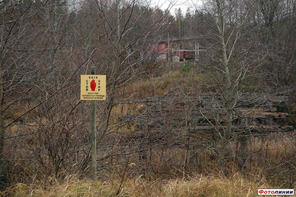 Вид из Эстонии в сторону России на границе, желтый знак предупреждает людей о границе